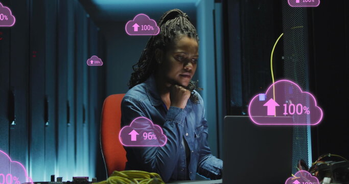 Image of cloud with uploading over african american woman working on laptop in server room