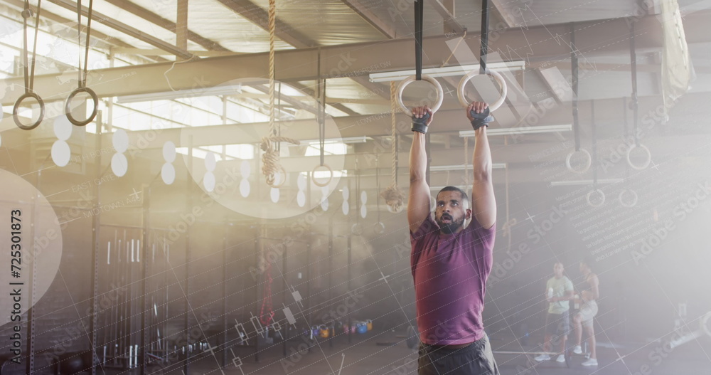Aufkleber image of data processing on interface over biracial man cross training using gym rings at gym