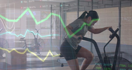 Image of data processing on graph over biracial woman cross training on elliptical at gym
