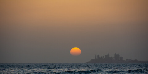 Sunset over the sea with a city in silhouette