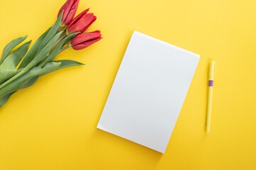 Top view of yellow desk with blank notebooks mockup with pencil and tulips. notebook