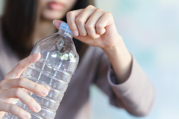A woman opens the cap of a water bottle to drink. Health care concept.