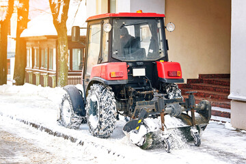 Machinery cleaning street from snow and ice after blizzard. Tractor with rotating brush clean snow...