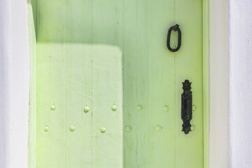 Green-painted vintage wooden door with metal handle close up.