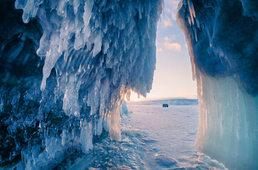 Ice cave with icicles in Baikal lake at sunset. Winter landscape of Baikal lake, Russia