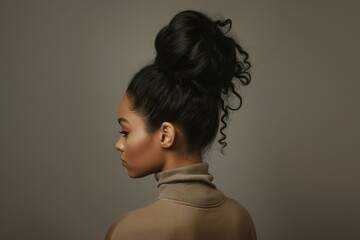 young woman with big voluminous hair bun, studio shot, neutral background