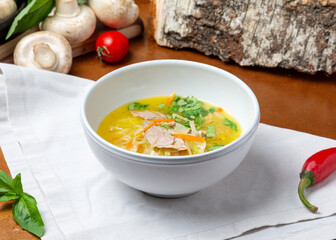 Chicken noodle soup in a plate on a wooden background