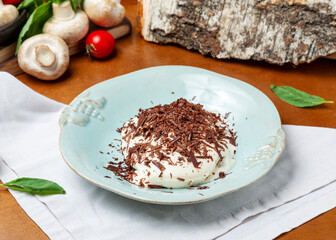 Tiramisu with chocolate chips in a plate on a wooden background