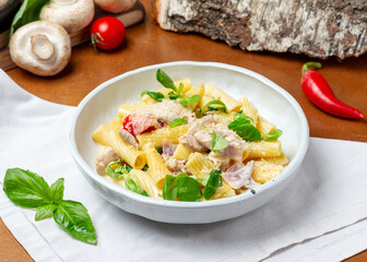 Pasta with chicken and cheese in a plate on a wooden background