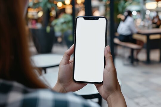 Mockup image of a woman holding smartphone with white screen in cafe
