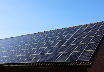 Naklejka premium Solar panels on a roof with blue sky and sunshine in the background. Solar energy and electricity production. Photovoltaic panels.