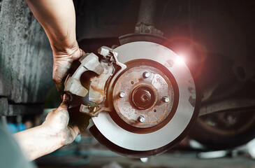 Close-up of a mechanic's hands working on a car's disc brake system, highlighting maintenance and...