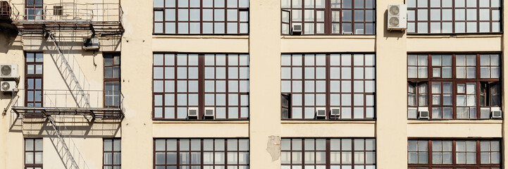 Wall of an industrial building with large glass windows. Wide panorama.