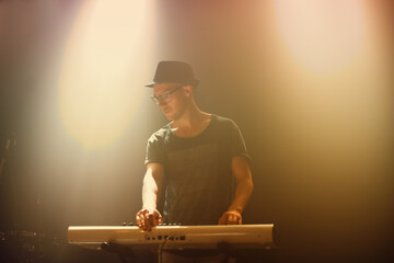 Music, concert and man playing keyboard for performance at night with glasses in entertainment....