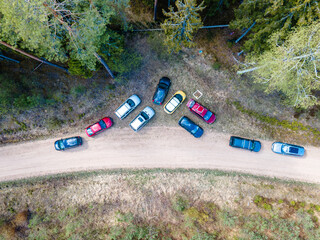aerial view of cars parked in a random pattern on a dirt road surrounded by forest - a unique...