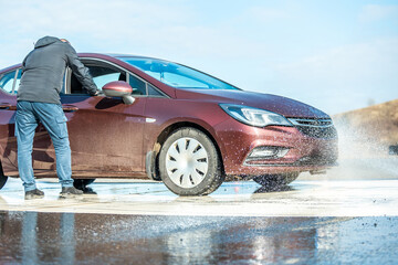 dynamic car braking test on wet road surface with water splashes and orange traffic cones, vehicle...