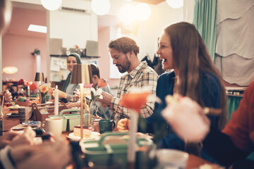 Diverse group of friends and family smiling and talking while taking an arts and crafts class during a bonding activity at the weekend