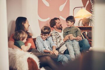 Smiling mother and father sitting with their three cute young boys while having fun in an arts and crafts cafe during a weekend family activity