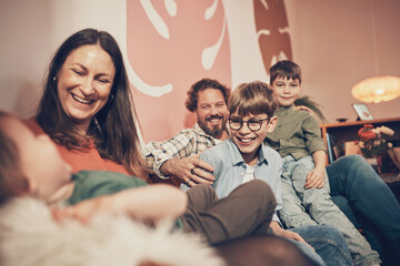 Mother and father with their three adorable young sons laughing while having fun in an arts and crafts cafe during a weekend family activity
