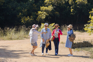 Group of Asian retirement women traveling, hiking, walking together in park, senior pensioner friends spend time exercise trekking in forest, elderly tourist recreation relationship lifestyle day trip