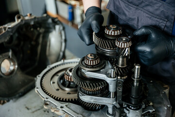 a disassembled gearbox in the hands of an experienced car mechanic who repairs broken mechanisms...