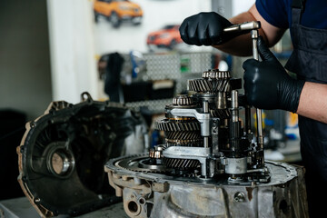 a disassembled gearbox in the hands of an experienced car mechanic who repairs broken mechanisms and parts in a car