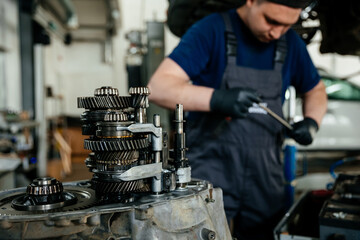 Repair of the manual gearbox of the car at the service station, focus on the disassembled mechanism, which the hands of the craftsman are engaged in