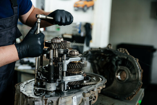 Repair of the manual gearbox of the car at the service station, focus on the disassembled mechanism, which the hands of the craftsman are engaged in