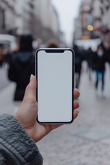 Mockup image of a smartphone with a white screen in a woman's hand on the background of the street