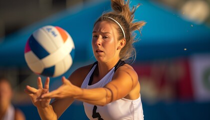 Young blonde woman playing beach volleyball, with white top, background blurred, she is throwing the ball up to serve, concentrated facial expression