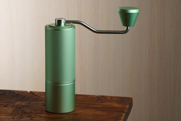 Green manual coffee grinder on a wooden table.