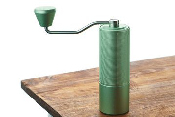 Green manual coffee grinder on the edge of a wooden table.