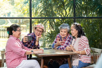 Group elderly mature business owner friends meeting in eatery restaurant using phone selfie take photo together, senior pension female happy free time celebation holiday, wellness aging care lifestyle