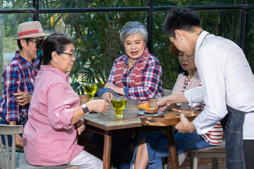 Group of elderly Asian friends enjoy Tea time in cafe with cake, talking, luaghing enjoy free time holiday after retirement, senior pension females spend time together in coffee shop meeting lifestyle