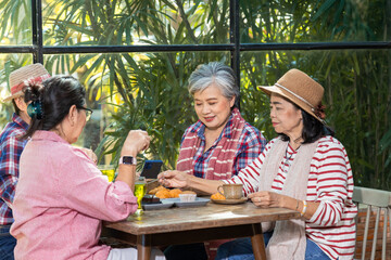 Group of elderly Asian friends enjoy drinking Tea in cafe talking, luaghing enjoy free time holiday after retirement, senior pension females happy spend time together in coffee shop meeting lifestyle