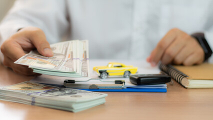 Closeup hand giving a car key and money for loan credit financial and rental. car loan concept, trade car for cash concept, finance concept. Buying or selling new or used vehicle. Car keys on table. - obrazy, fototapety, plakaty