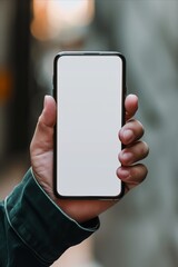 Mockup image of male hand holding black smartphone with blank white screen on blurred background