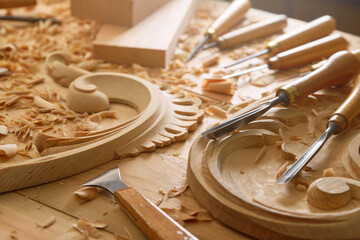 In the workshop, a woodcarver sculpts floral patterns into the heart of a wooden block. Warm hues...