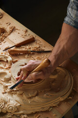 Carving wooden furniture. Carpenter using tool making artistic wood carving.