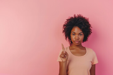 Portrait of african american woman isolated on pink background. dark skinned woman shows finger at upper corner isolated over pink background. Banner. Copy space.