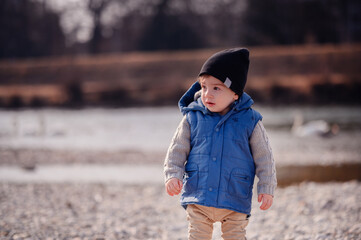 Thoughtful young child in a knit sweater and vest, contemplating during a cool outdoor day