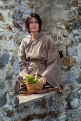 Poor medieval maid with herb bowl at castle
