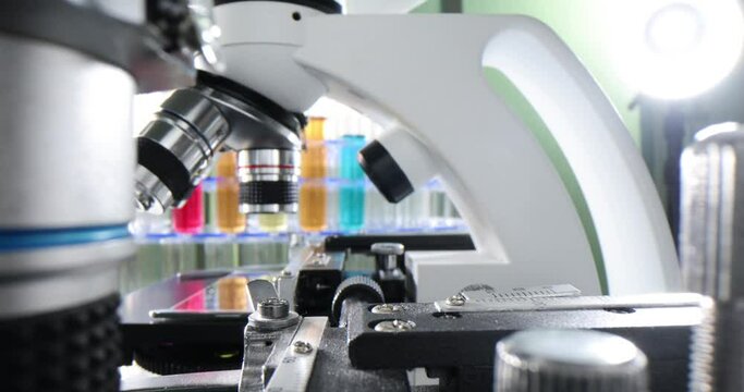 Colorful liquid laboratory test tubes and a row of microscopes