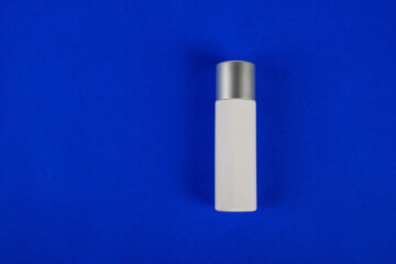 Plastic white tube for cream or lotion. Skin care or sunscreen cosmetic on blue background 