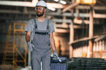 Front view, walking forward. Young factory worker in grey uniform