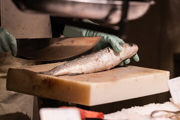 Unrecognizable fishmonger holding a fish for filleting at a market