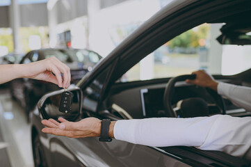 Cropped photo of customer buyer client receive keys fob keyless system from salesman sit in car...