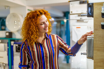 Portrait of buyer in bathroom store. Redhead woman is choosing equipment for her apartment.