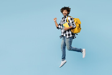 Full body young Indian boy student wear shirt casual clothes backpack bag hold books jump high do...