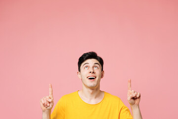 Young smiling happy fun Caucasian man wears yellow t-shirt casual clothes point index finger...
